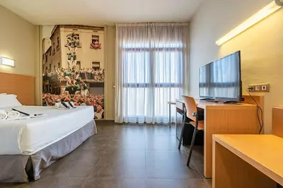 a hotel room with a bed and a desk and a television at Hotel Pere III El Gran in Vilafranca del Penedès