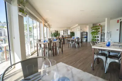 a restaurant with tables and chairs and windows at Dynamic Hotels Caldetes Barcelona in Caldes d'Estrac