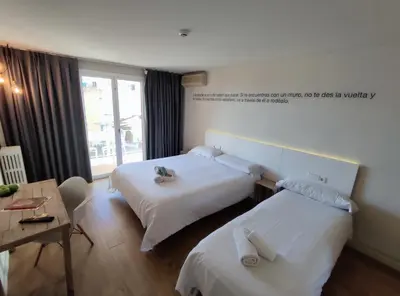 a hotel room with two beds and a table at Dynamic Hotels Caldetes Barcelona in Caldes d'Estrac