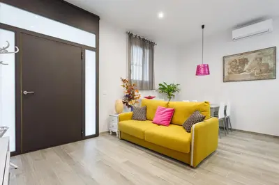 a yellow couch with pink pillows in a living room at Beautiful Apartment 20 minutes from city center in Hospitalet de Llobregat