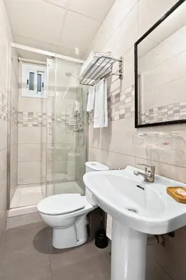 a white bedroom with a bed and a window at Hostal Santa Ana in Barcelona