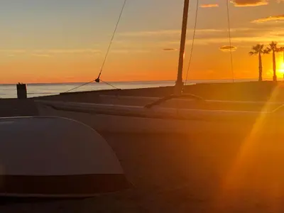 a boat sitting on the beach with the sunset at Espectacular ático dúplex con vistas al mar in Cunit