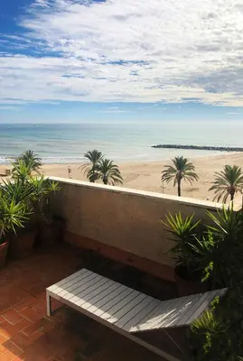 a bench sitting on a balcony overlooking the beach at Espectacular ático dúplex con vistas al mar in Cunit