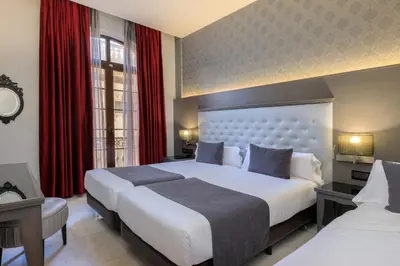 a hotel room with two beds and red curtains at Hotel Ciutadella Barcelona in Barcelona