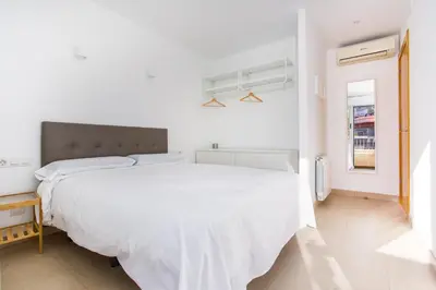a white bedroom with a large bed and a window at Feriapiso Apartments Palmer in Hospitalet de Llobregat