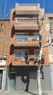 a tall brick building with a tree in front of it at Feriapiso Apartments Palmer in Hospitalet de Llobregat