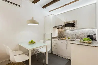 a kitchen with white cabinets and a table and chairs at Ola Living Born in Barcelona