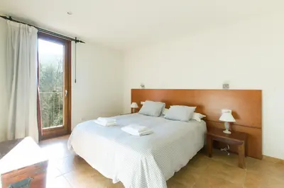a bedroom with a large white bed with a window at Masia el Prat in El Pont de Vilomara