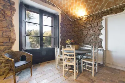 a dining room with a table and chairs and a stone wall at Masia el Prat in El Pont de Vilomara