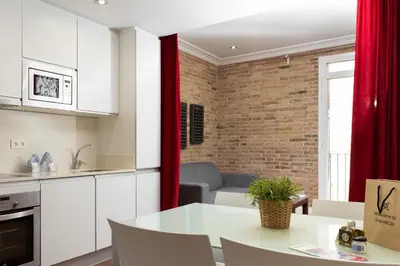 a kitchen and living room with white cabinets and a table at Enjoybcn Gaudi Apartments in Barcelona