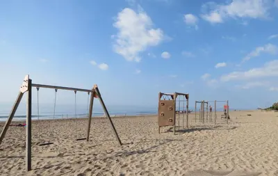 a row of playground equipment on a sandy beach at GAVA4 BEACHFRONT Apartment BARCELONA in Gavà