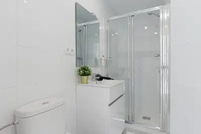 a white bathroom with a shower and a toilet at Key Barcelona HOUSING (Carrer Girona) in Barcelona