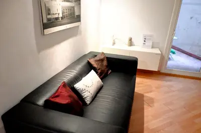 a black leather couch in a living room with pillows at Homenfun Barcelona Sagrada Familia Glories in Barcelona