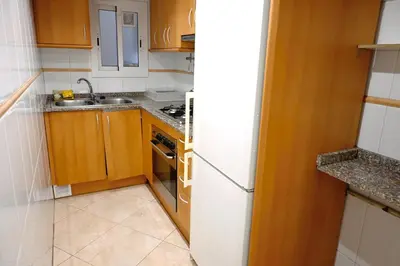 a kitchen with wooden cabinets and a white refrigerator at Homenfun Barcelona Sagrada Familia Glories in Barcelona