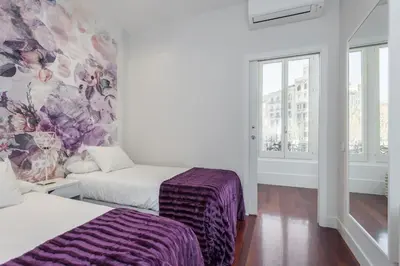 a bedroom with two beds and a floral wall at Art House Granvia in Barcelona