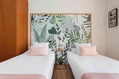 two beds in a room with a floral wallpaper at Art House Sagrada Familia in Barcelona
