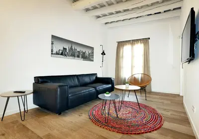 a living room with a black leather couch and two tables at ClassBedroom Port Ramblas in Barcelona