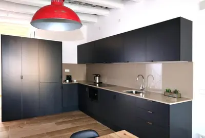 a kitchen with black cabinets and a red light fixture at ClassBedroom Port Ramblas in Barcelona