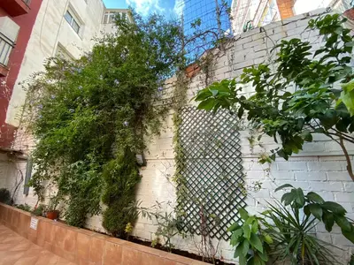 a white brick wall with a chain link fence at Cozy Suite apartment, WiFi! in Santa Coloma