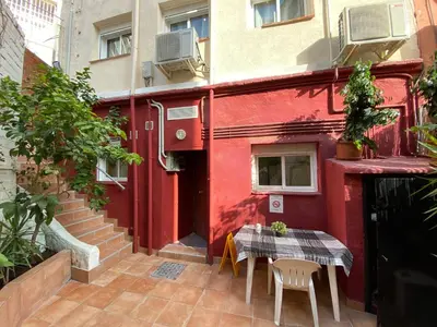 a red building with a table and chairs in front of it at Cozy Suite apartment, WiFi! in Santa Coloma