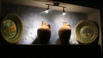 three vases on a shelf with plates on a wall at Comarquinal Bioresort Penedes in San Quintín de Mediona