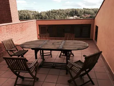 a wooden table and chairs on a patio at Aparthotel del Golf in Sant Cugat del Vallès