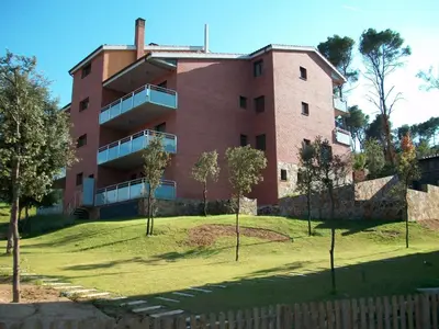 a large brick building with trees in front of it at Aparthotel del Golf in Sant Cugat del Vallès