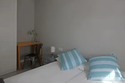 a bedroom with a bed with two pillows and a desk at Fridays Flats Casa Lemonade in Hospitalet de Llobregat