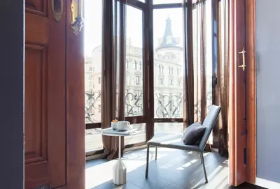 a room with a window with a chair and a table at DestinationBCN Universitat Apartments in Barcelona
