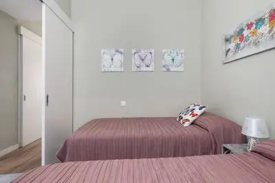 a white room with two beds and a mirror at Camp Nou , Fira Barcelona Apartment in Hospitalet de Llobregat