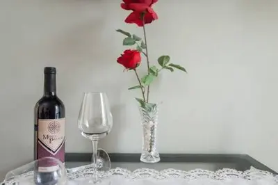 a vase with a red rose and a bottle of wine at Camp Nou , Fira Barcelona Apartment in Hospitalet de Llobregat