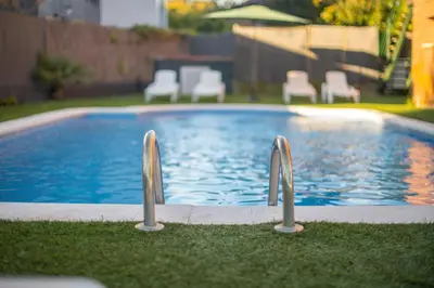 a swimming pool with two metal bars in the grass at Aparthotel Marsol in Castelldefels
