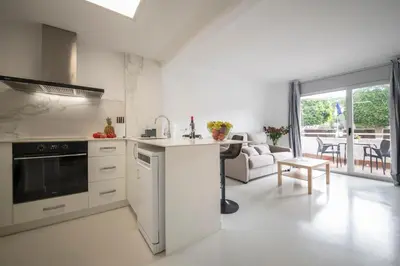 a kitchen with a stove top oven next to a living room at Aparthotel Marsol in Castelldefels