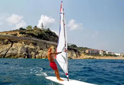 a man on a surfboard with a sail on the water at Casablanca Suites - Adults Only in Calella