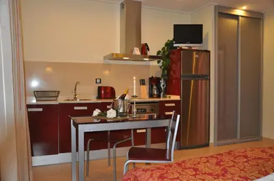 a small kitchen with a table and a refrigerator at Casablanca Suites - Adults Only in Calella
