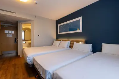 two beds in a hotel room with blue walls at Travelodge Barcelona Poblenou in Barcelona