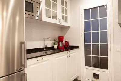 a kitchen with white cabinets and a stainless steel refrigerator at Rambla Poblenou&Mar Bella Beach in Barcelona