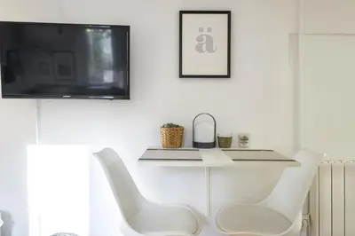 a white chair in a living room with a tv at NEW Renovated COZY APPARTMENT CENTRIC in Barcelona