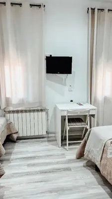 a white room with a desk and a tv at Hostal Ruta de Francia in Barcelona
