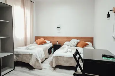 a room with two beds and a table and a desk at Hostal Ruta de Francia in Barcelona