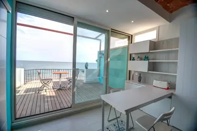 a kitchen with a table and a balcony with the ocean at Blue sea front by Hello Homes Sitges in Sitges