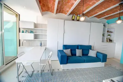 a living room with a blue couch and a table at Blue sea front by Hello Homes Sitges in Sitges