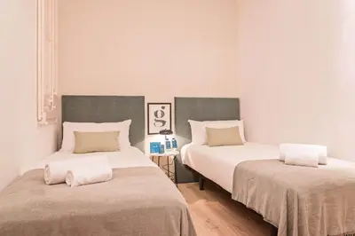 two beds in a room with white walls and wooden floors at Sweett - The Roca House in Barcelona