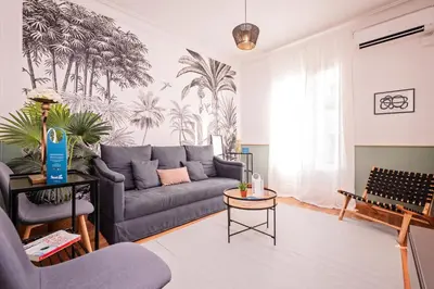 a living room with a gray couch and palm trees mural at Sweett - The Roca House in Barcelona