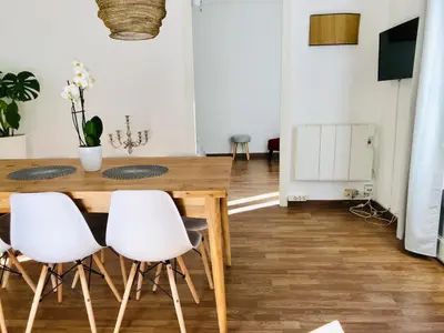 a dining room with a wooden table and white chairs at Big and Bright Apartment BCN in Barcelona