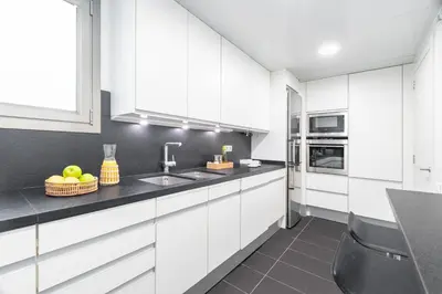 a kitchen with white cabinets and black counter tops at Aspasios Paseo de Gracia Apartments in Barcelona