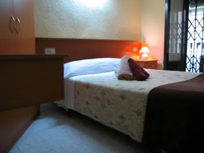 a bedroom with a bed and a dresser with a lamp at PENSIÓN Colmenero in Barcelona