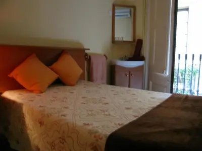 a bedroom with a bed with orange pillows and a window at PENSIÓN Colmenero in Barcelona