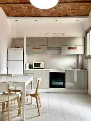 a kitchen with a white table and chairs and a white counter at Charm Miró in Barcelona