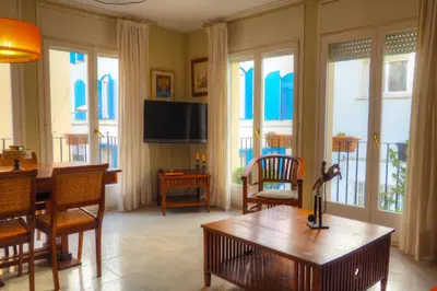 a living room with a table and chairs and windows at Center Family Apartment by Hello Homes Sitges in Sitges